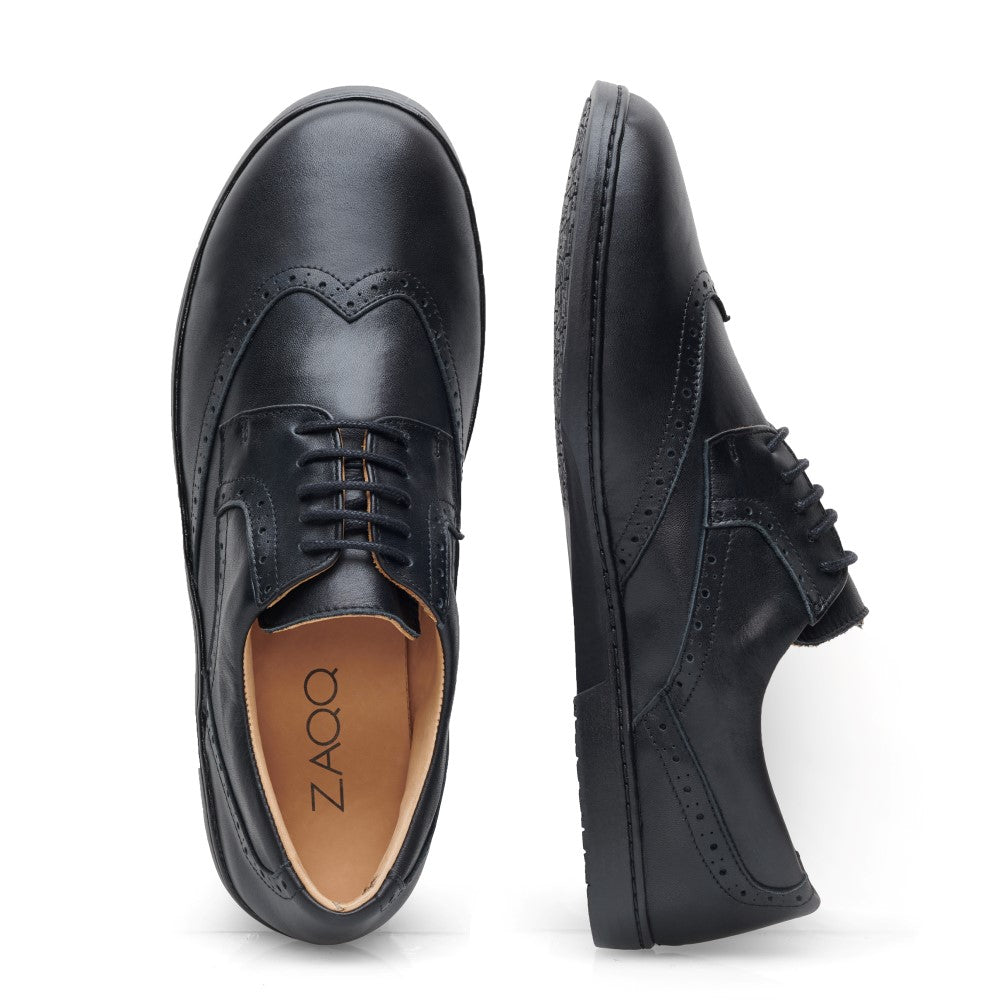 Seitenansicht eines Paars BRIQ Brogue Waterproof Black von ZAQQ, aus schwarzem Leder gefertigt und mit dekorativen Perforationen für einen zeitlosen Look.