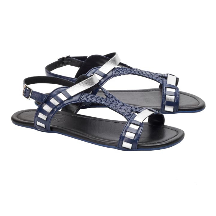 Wir präsentieren das BLINQ Dark Blue von ZAQQ: ein Paar elegante dunkelblaue Sandalen mit geflochtenem Design und metallisch-silbernen Akzenten. Diese Sandalen verfügen über verstellbare Knöchelriemen und flache Kautschuksohlen und bieten schicken Komfort für jeden Anlass.