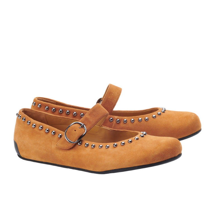 Die DIEQO Brown Flats von ZAQQ sind aus samtigem hellbraunem Leder gefertigt und verfügen über silberne Nietenakzente sowie einen Riemen mit silberner Schnalle. Diese eleganten Ballerinaschuhe haben eine abgerundete Spitze und sind auf einem weißen Hintergrund zu sehen.