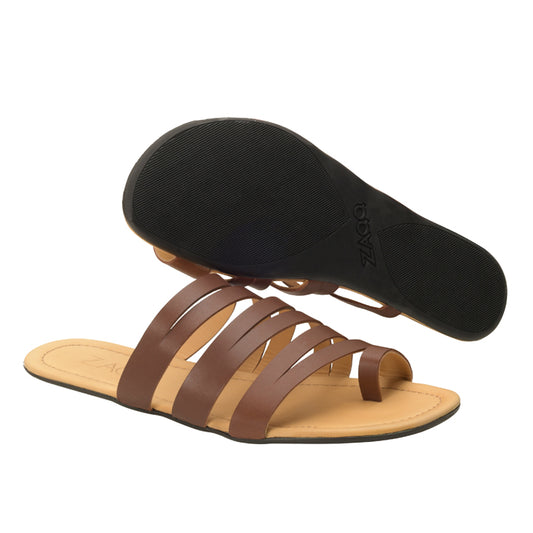 Die FLAQE Dark Brown Sandalen von ZAQQ haben ein braunes Riemchendesign aus Premium Nappaleder mit flachen Sohlen. Eine Sandale steht aufrecht, um das obere Design zu zeigen, während die andere umgedreht ist, um die schwarze Sohle freizugeben und so ihren hohen Tragekomfort hervorzuheben.