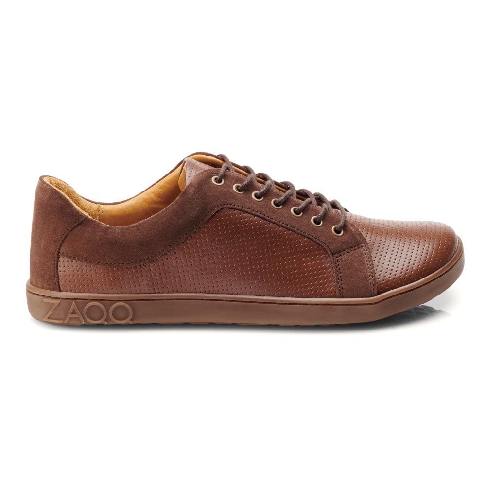 Der QORE Low Rafter von ZAQQ ist ein stylischer brauner Ledersneaker mit perforiertem Design und hellbraunen Akzenten. Dieser atmungsaktive Sneaker hat einen Schnürverschluss und eine flache Gummisohle, auf deren Seite das ZAQQ-Logo eingeprägt ist.