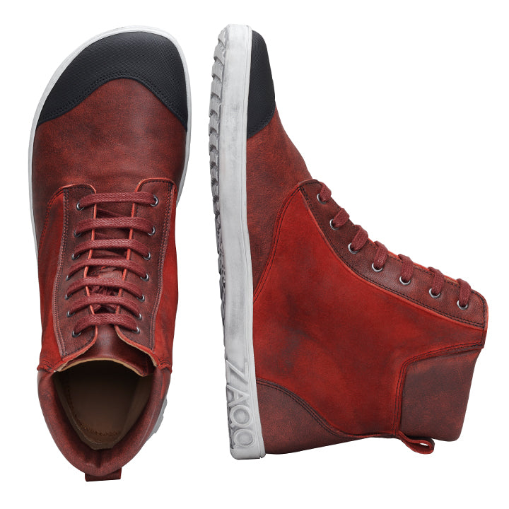 Der CHICAQO Red von ZAQQ ist ein Paar High-Top-Sneaker aus Nappa- und Veloursleder mit schwarzer Zehenkappe und weißer, flexibler Sohle. Ein Schuh ist aufrecht für eine Seitenansicht ausgestellt, während der andere seine Schnürsenkel und das schwarze Frontdetail von oben hervorhebt. Der Markenname ZAQQ ist auf der Sohle sichtbar.