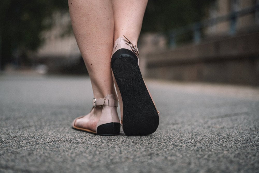 Ein Paar elegante beige Riemchensandalen mit Fesselriemen und flacher Sohle, gefertigt aus weichem Nappaleder, bekannt als CLIQ Beige von ZAQQ.