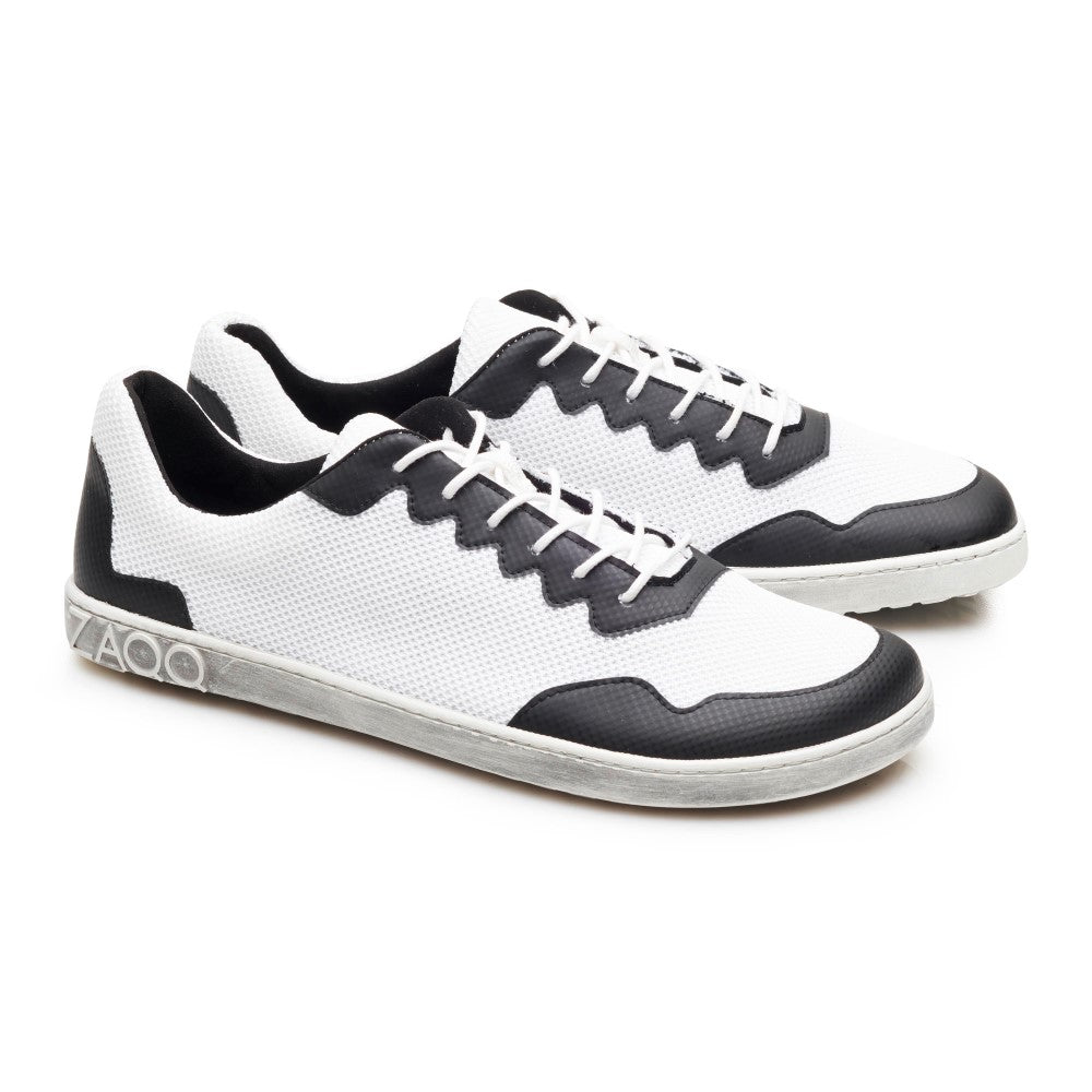 Wir präsentieren die DUPLEQ Black White Vegan Sneaker von ZAQQ: Diese stylischen schwarz-weißen Schuhe haben weiße Schnürsenkel und Sohlen und sind mit einem strukturierten Muster aus atmungsaktivem Meshgewebe gestaltet. Ein Logo ziert die Ferse und verleiht diesen veganen Barfußschuhen ein schlichtes Aussehen, da sie nebeneinander auf einem schlichten weißen Hintergrund stehen.