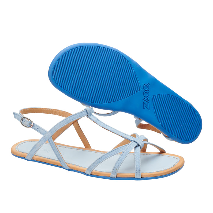 Wir präsentieren die QADA Blue von ZAQQ: ein schickes Paar Sandalen mit eleganten hellblauen Riemen und Schnallenverschluss. Diese Sandalen sind mit einer hochflexiblen Barfußsohle für überragenden Tragekomfort ausgestattet. Eine Sandale zeigt ihr schlankes Seitenprofil, während die andere die leuchtend blaue, strukturierte Sohle mit dem markanten ZAQQ-Logo offenbart.