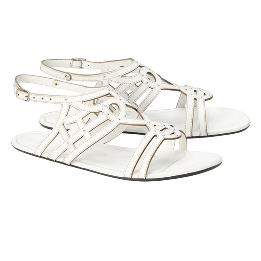 Entdecken Sie die QANQETA White von ZAQQ, ein Paar stilvolle weiße Ledersandalen aus hochwertigem Nappaleder mit einem aufwendigen Cut-out-Design und verstellbaren Knöchelriemen vor einem sauberen weißen Hintergrund.