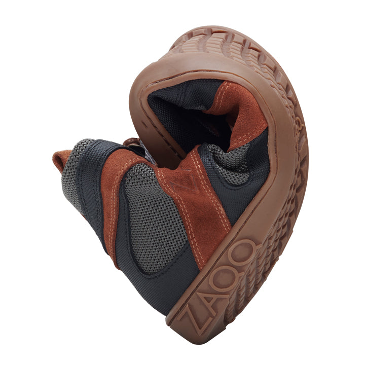 Der QINSLEY Brown von ZAQQ zeigt sein faltbares Design, da er sich mühelos in zwei Hälften falten lässt. Dieser stilvolle Barfußschuh aus Veloursleder und schwarzem Mesh ist mit einer strapazierfähigen braunen Gummisohle ausgestattet und trägt den Markennamen auf der Seite.