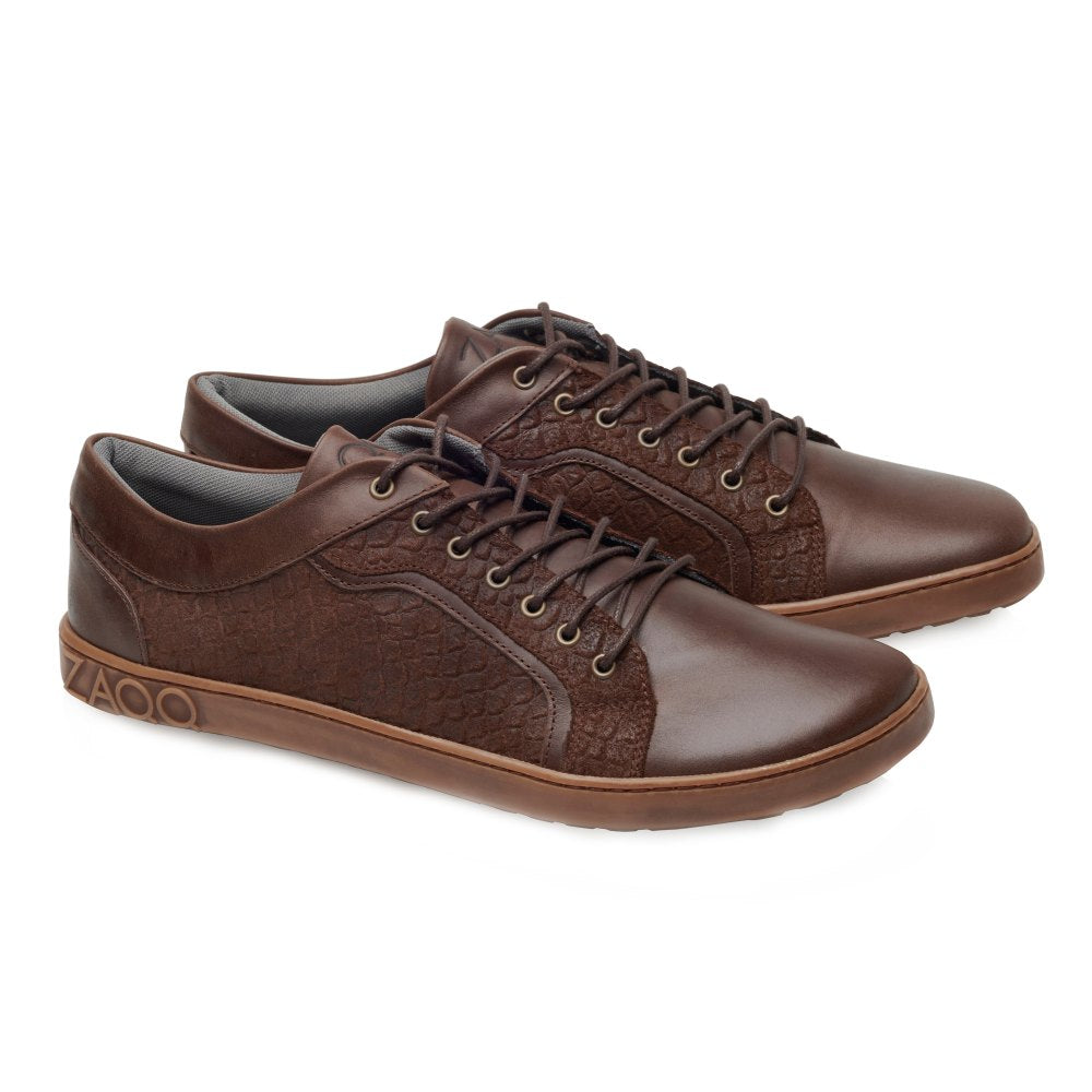 Die QODY Brown von ZAQQ sind schicke Leder-Sneaker mit strukturierten Seitenteilen und einem Logo an der Ferse. Diese Sneaker aus hochwertigem Nappa- und Veloursleder zeichnen sich durch ein schlichtes Design mit dunklen Schnürsenkeln und kontrastierenden hellbraunen Sohlen aus. Die flexible Barfußsohle sorgt für maximalen Komfort.