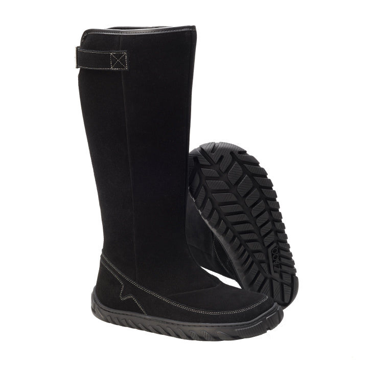 Ein Paar kniehoher QRAFT-Stiefel in Schwarz von ZAQQ sticht durch die ULTRAGRIP-Sohle mit strukturierter, profilierter Sohle hervor. Ein Stiefel steht aufrecht, während der andere geneigt ist, wodurch sowohl die aufwendigen Kontrastnähte als auch ein praktischer Klettverschluss an der Oberseite sichtbar werden.