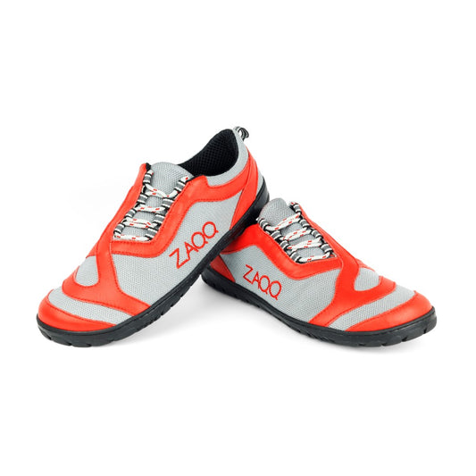 Die Sportschuhe ZAQQ QUIQ Trail Lightred verfügen über ein rot-graues Design mit atmungsaktiver Konstruktion, ergänzt durch eine schwarze Sohle und V-förmig gemusterte Schnürsenkel auf weißem Hintergrund – ideal für jedes Trail-Abenteuer.