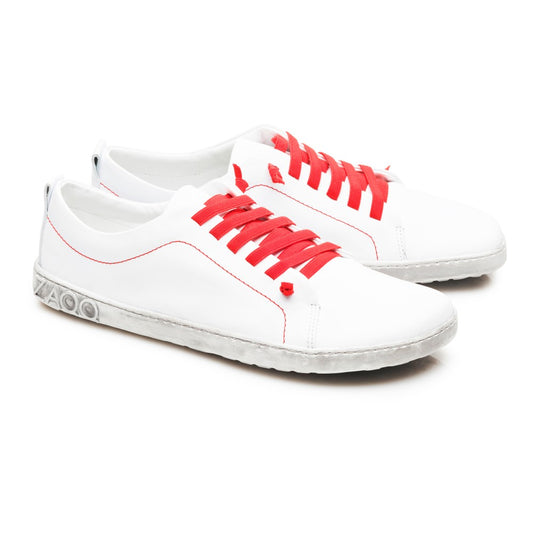 Wir präsentieren den STIQ White von ZAQQ, ein stylisches Paar Sneaker aus hochwertigem Nappaleder. Diese eleganten weißen Schuhe sind mit leuchtend roten Schnürsenkeln und Nähten akzentuiert. Sie haben eine graue, strukturierte Sohle und das dezente ZOO-Logo ist elegant auf der Ferse eingeprägt. Nebeneinander vor einem schlichten weißen Hintergrund präsentiert, verkörpern sie perfekt zeitgenössische Mode.