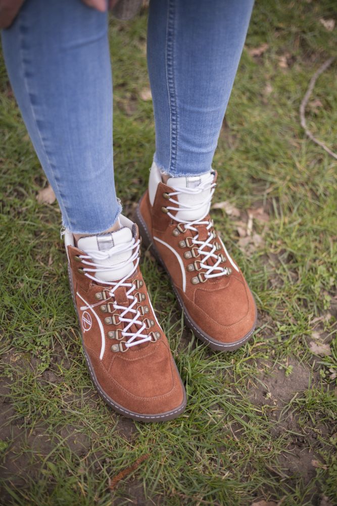 In der Szene steht jemand in Blue Jeans auf dem Rasen und trägt die wasserdichten Schuhe TREQ Cognac von ZAQQ. Die Kombination vermittelt ein lässiges Outdoor-Feeling.