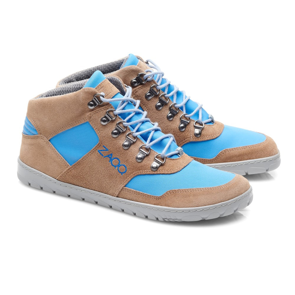 Die ZAQQ HIQE Mid Sky Waterproof Sneaker sind Mid-Top-Sneaker mit Einsätzen aus braunem Wildleder und blauem Stoff. Sie haben graue Schnürsenkel, silberne Ösen und eine hellgraue Sohle. Auf der Seite ist der Markenname ZAQQ aufgedruckt.