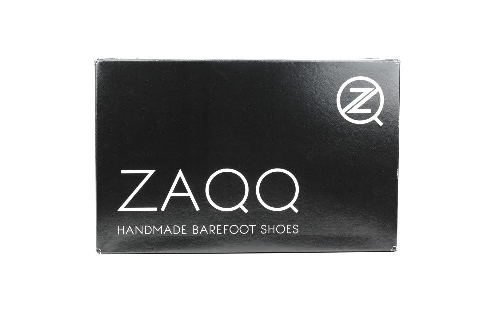 Auf dem schwarzen Schuhkarton steht in Weiß der Text „ZAQQ CLIQ WHITE“ mit einem „Z“-Logo in der oberen rechten Ecke, was die Eleganz der Marke widerspiegelt.