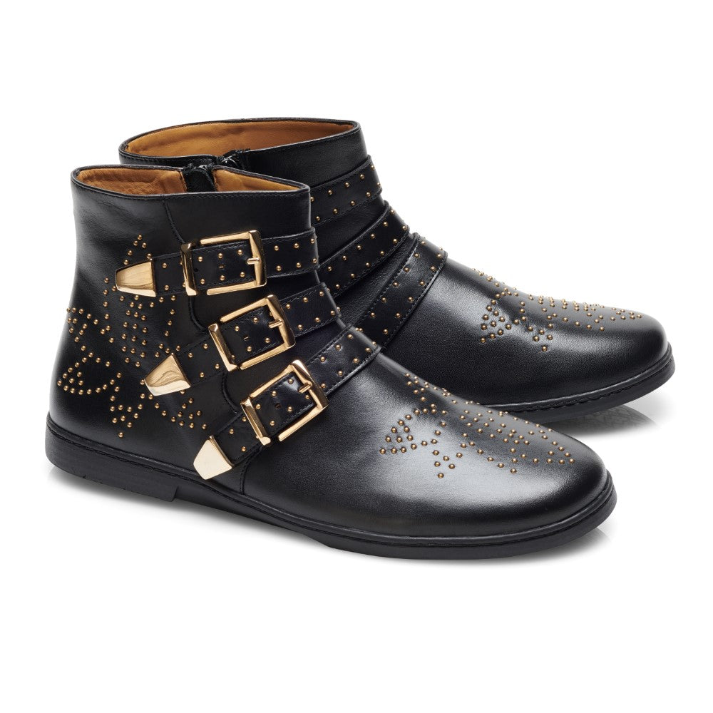 Ein Paar QLANCE Black Gold Stiefeletten von ZAQQ strahlt schwarz-goldene Eleganz mit einem dekorativen Muster aus goldenen Nieten aus. Diese atemberaubenden Barfuß-Stiefel werden durch drei glänzende goldene Schnallen an der Seite akzentuiert und verfügen über einen praktischen Reißverschluss, alles wunderschön vor einem makellosen weißen Hintergrund präsentiert.