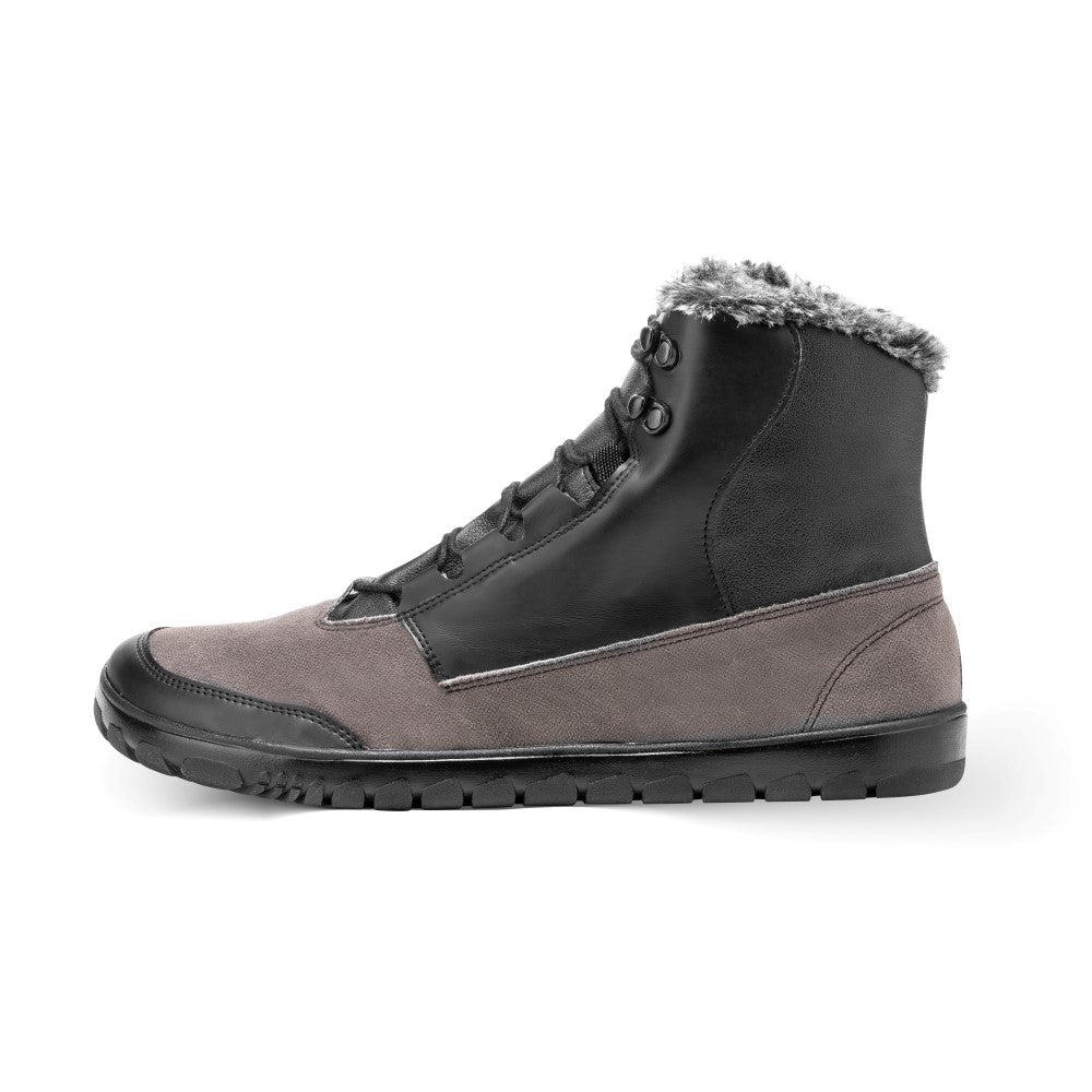 Der QUEST Black Waterproof von ZAQQ ist ein High-Top-Schuh aus grauem Wildleder im unteren Teil und schwarzem Leder im oberen Teil. Er verfügt über ein Schnürdesign und eine robuste schwarze Sohle. Mit einem Kunstfellbesatz am Knöchel gefüttert, bietet er zusätzliche Wärme und Stil für Outdoor-Abenteuer.